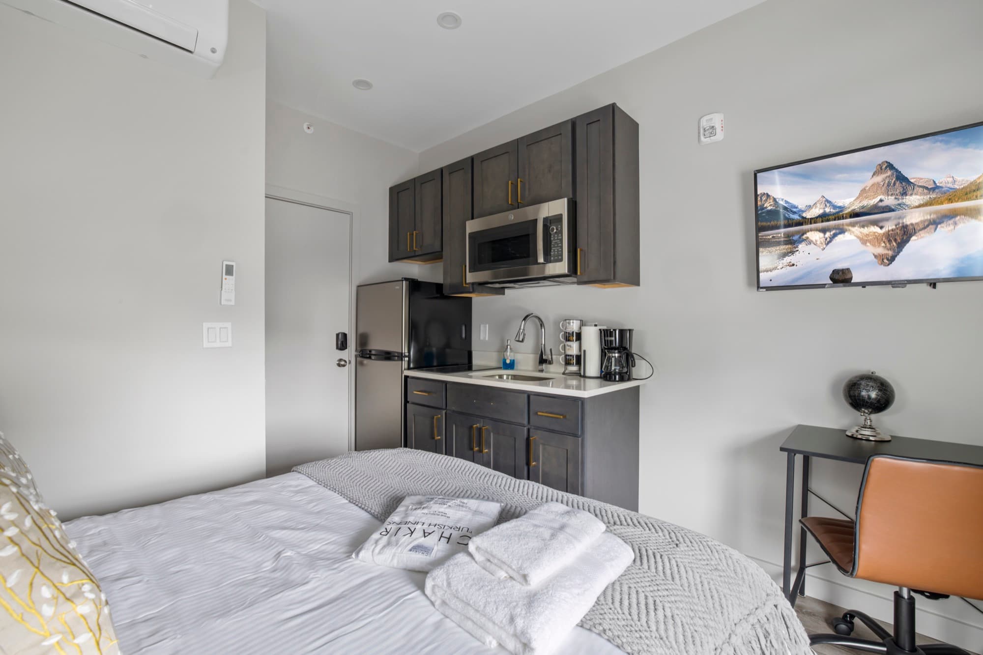 Room from the foot of the bed, kitchenette wall and TV