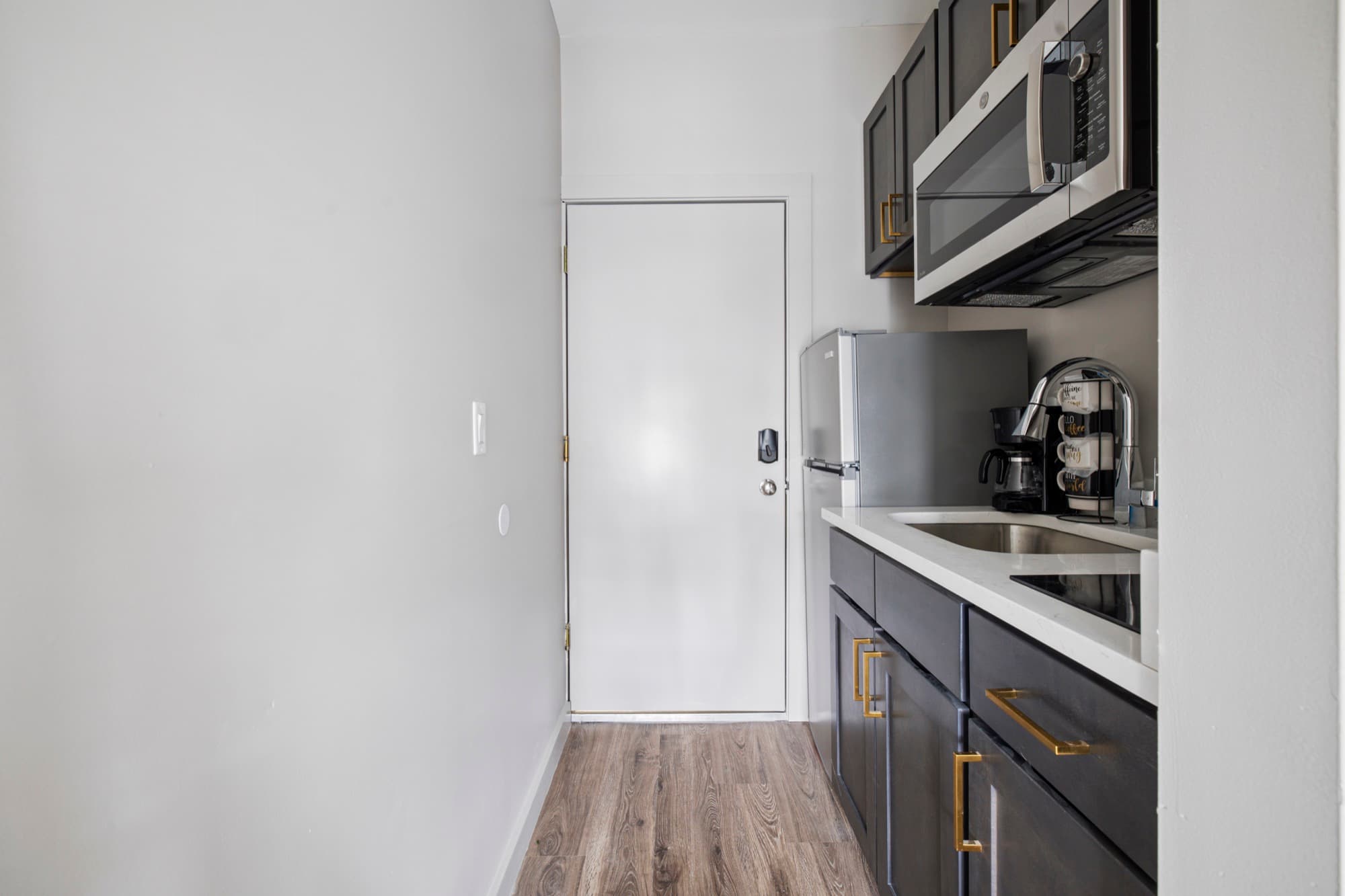 Kitchenette with dark cabinets and a coffee station